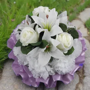 a funeral posy of artificial silk roses and lily flowers in shades of lilac and white